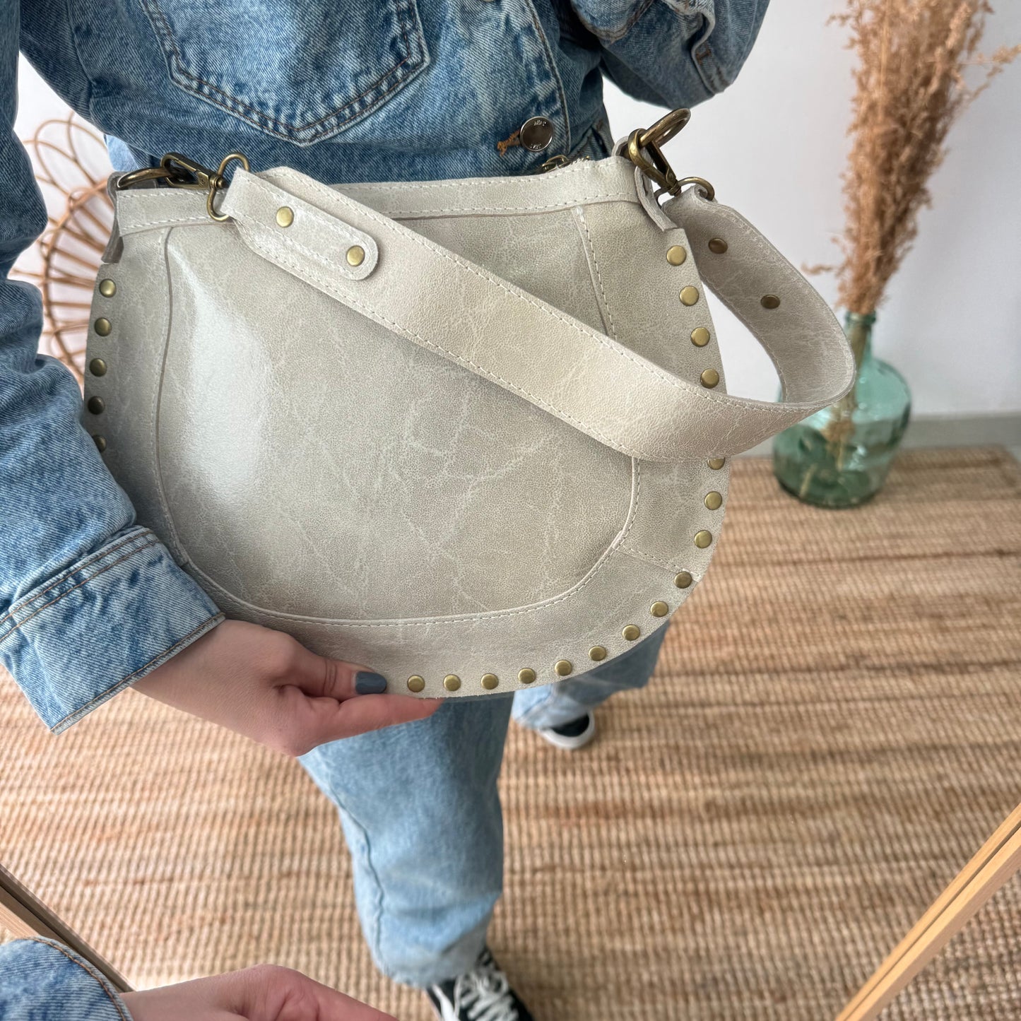Bandolera ovalada piel tachuelas beige iniciales bordadas herrajes cobre