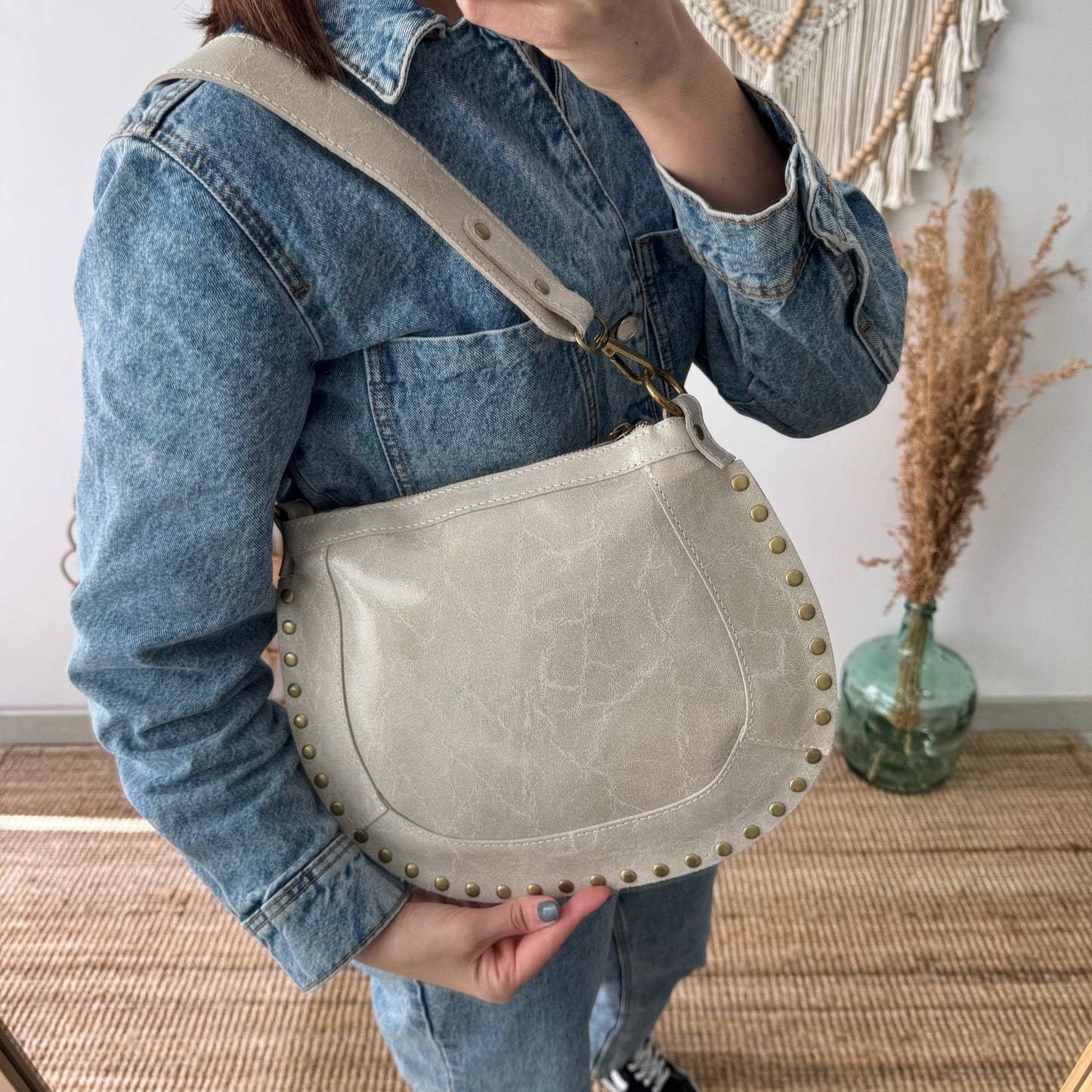 Bandolera ovalada piel tachuelas beige iniciales bordadas herrajes cobre