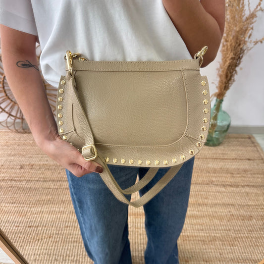 Bandolera ovalada piel tachuelas taupe iniciales bordadas