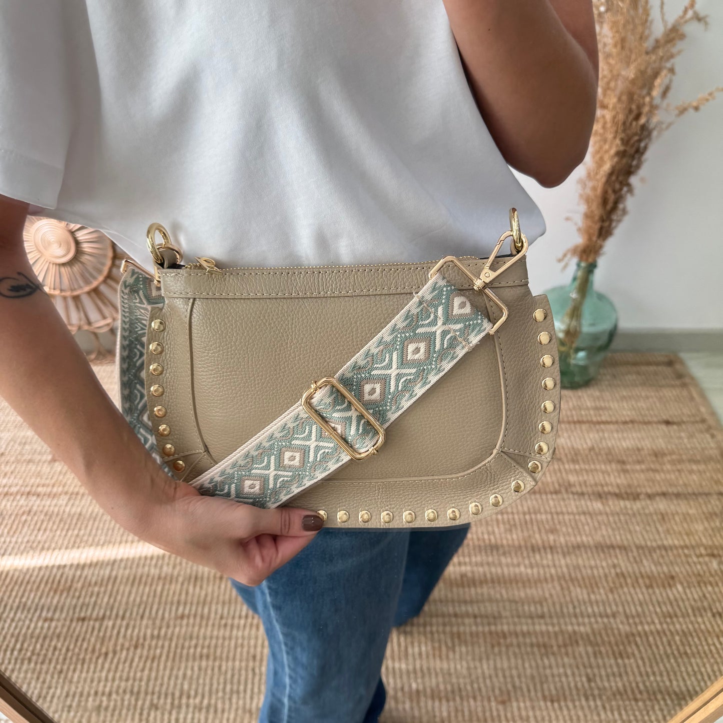 Bandolera ovalada piel tachuelas taupe iniciales bordadas