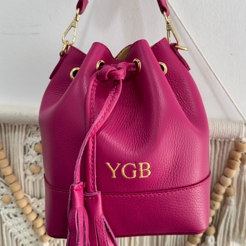 Bolso bucket piel fucsia pompón iniciales bordadas