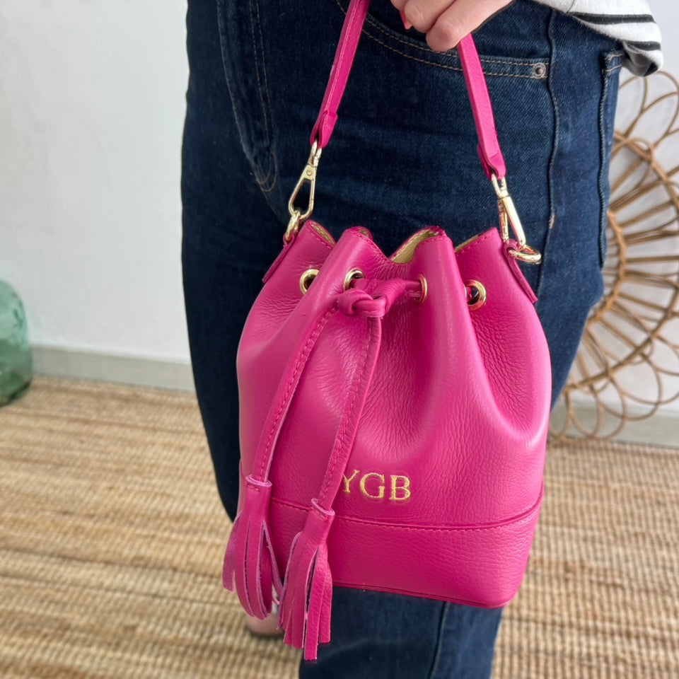 Bolso bucket piel fucsia pompón iniciales bordadas
