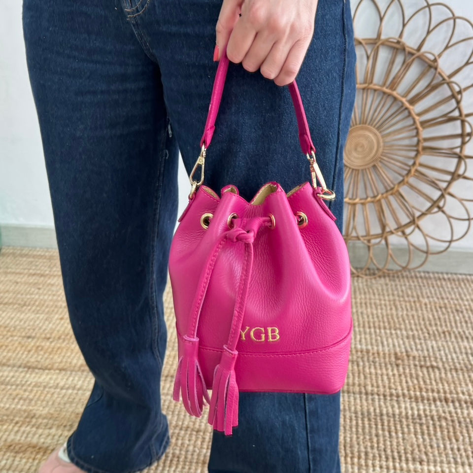 Bolso bucket piel fucsia pompón iniciales bordadas
