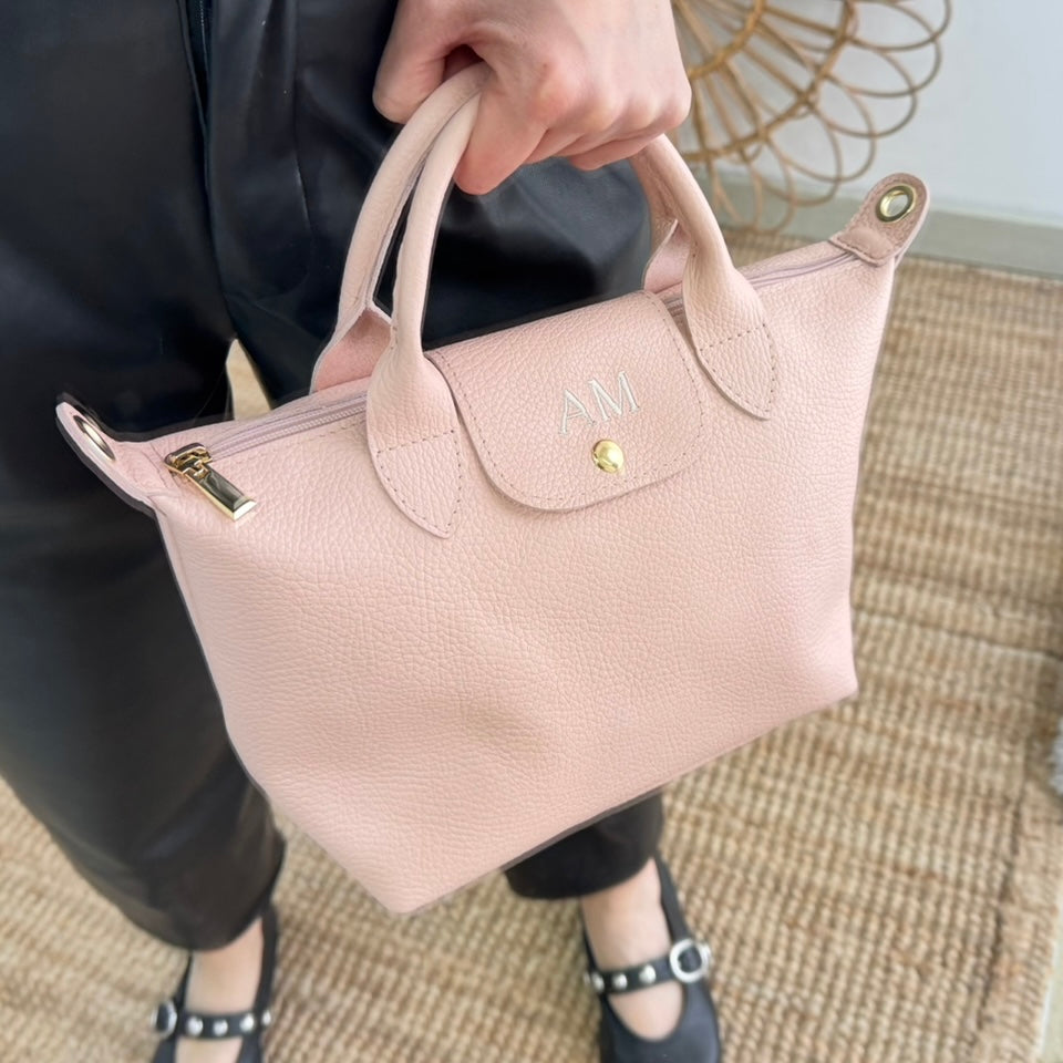 Bolso ovalado piel rosa solapa iniciales bordadas