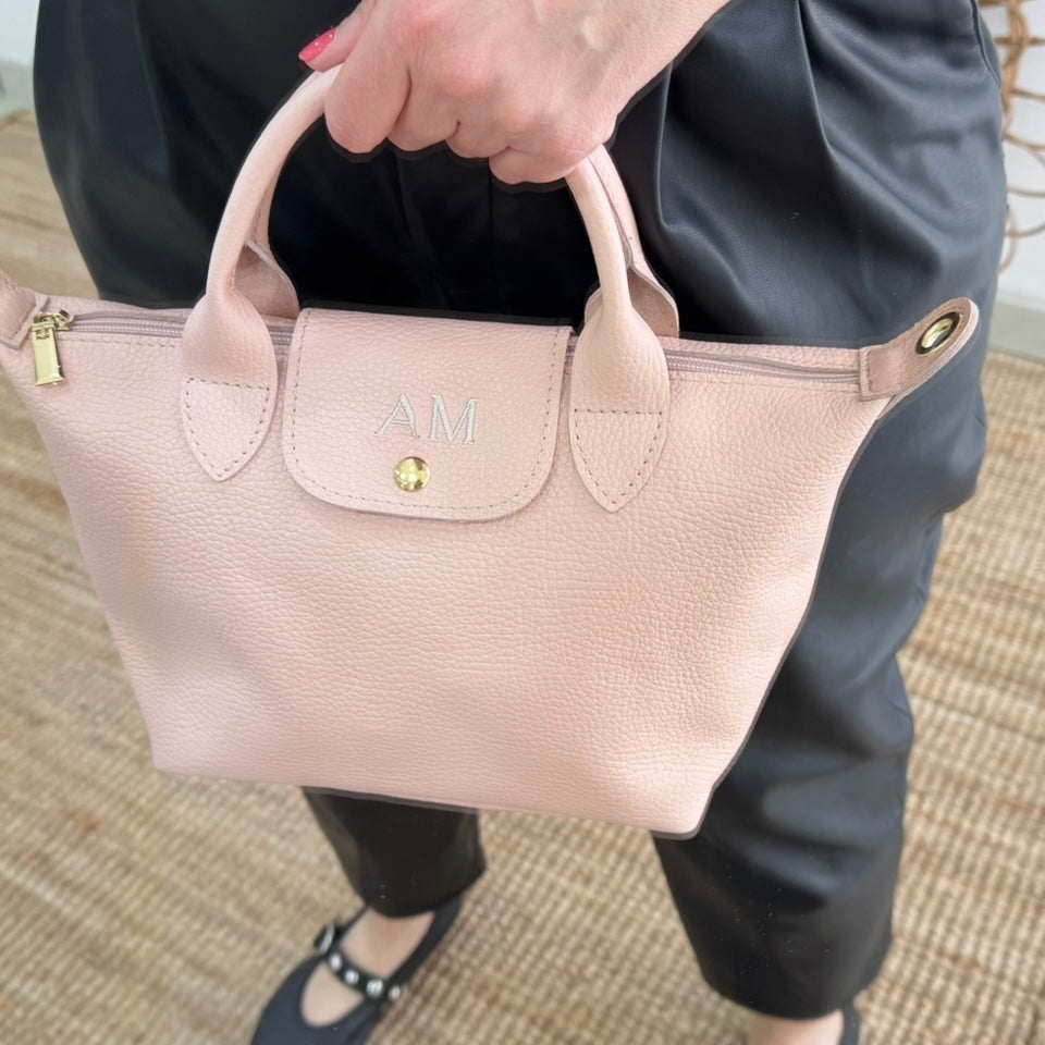 Bolso ovalado piel rosa solapa iniciales bordadas