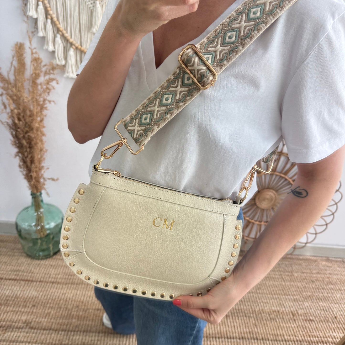 Bandolera ovalada piel tachuelas beige iniciales bordadas