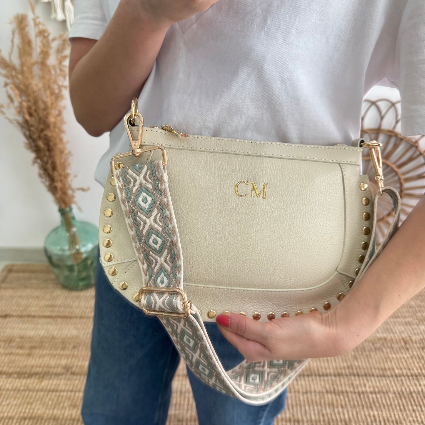 Bandolera ovalada piel tachuelas beige iniciales bordadas