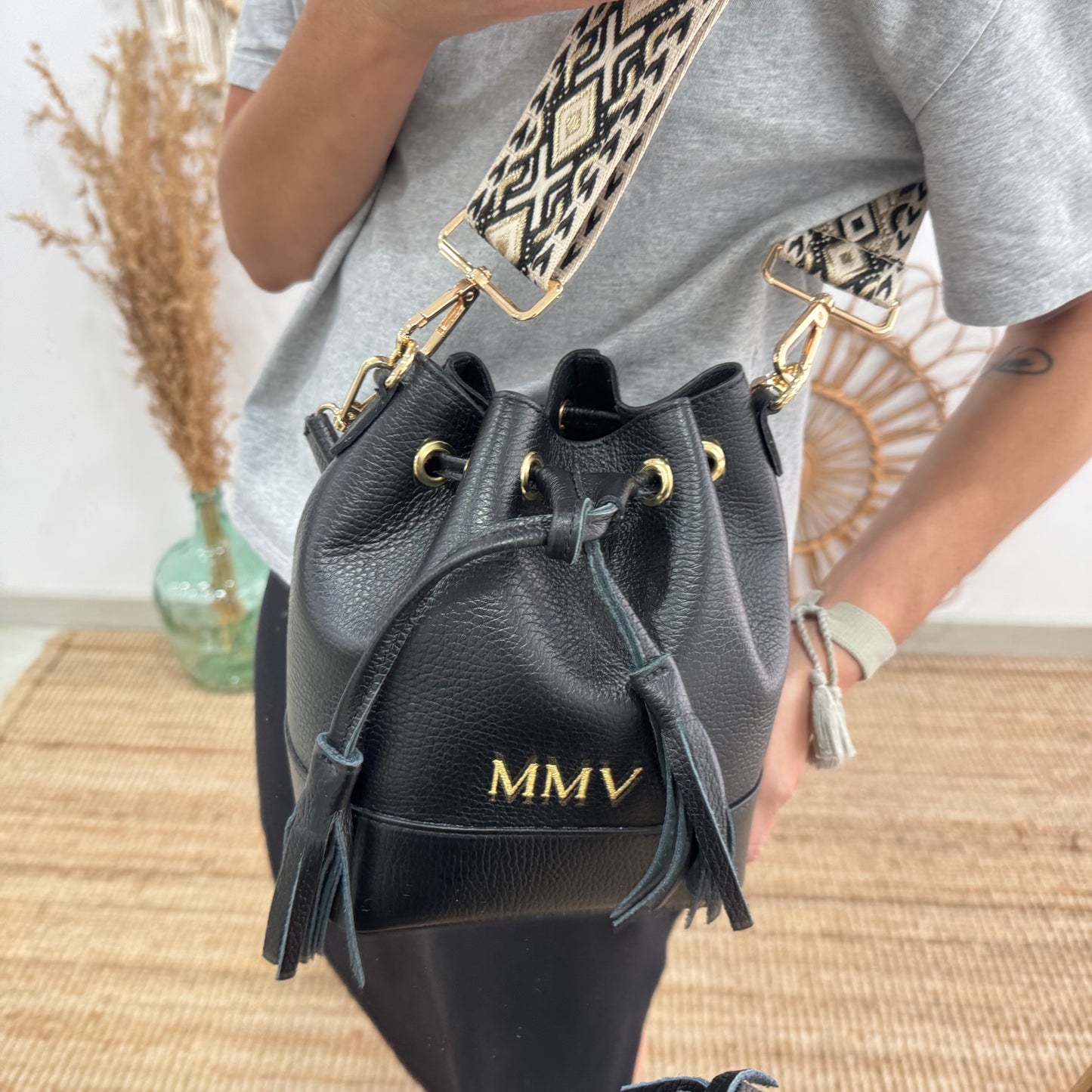 Bolso bucket piel negro pompón iniciales bordadas