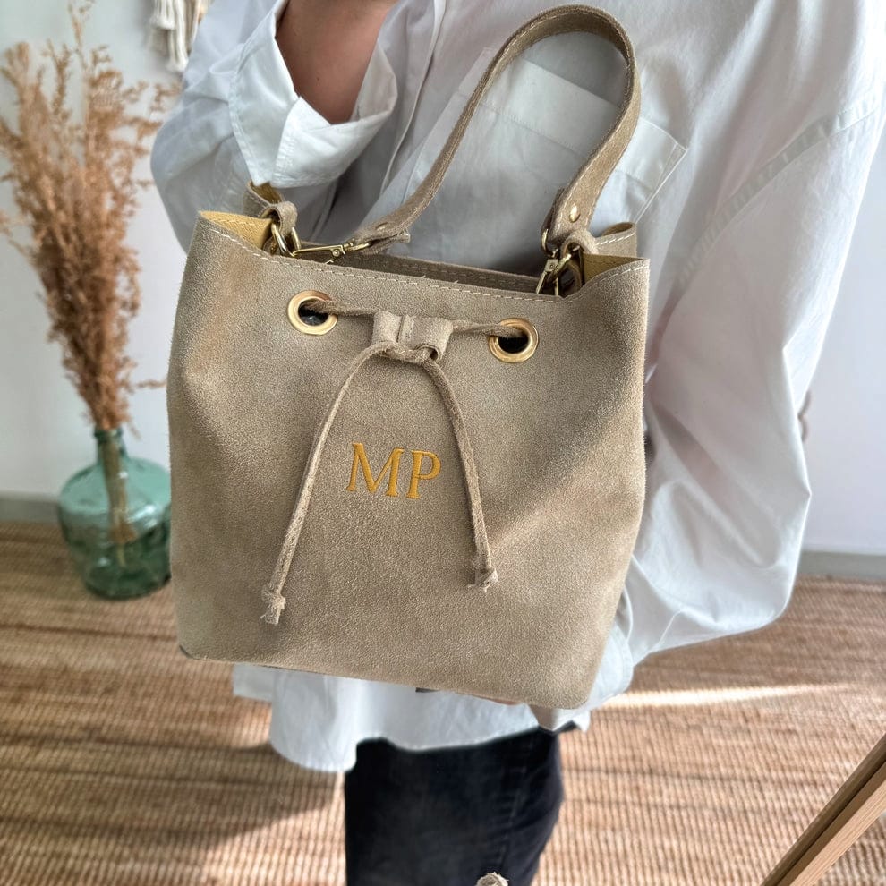 Bolso bucket serraje beige arandelas herraje dorado iniciales bordadas