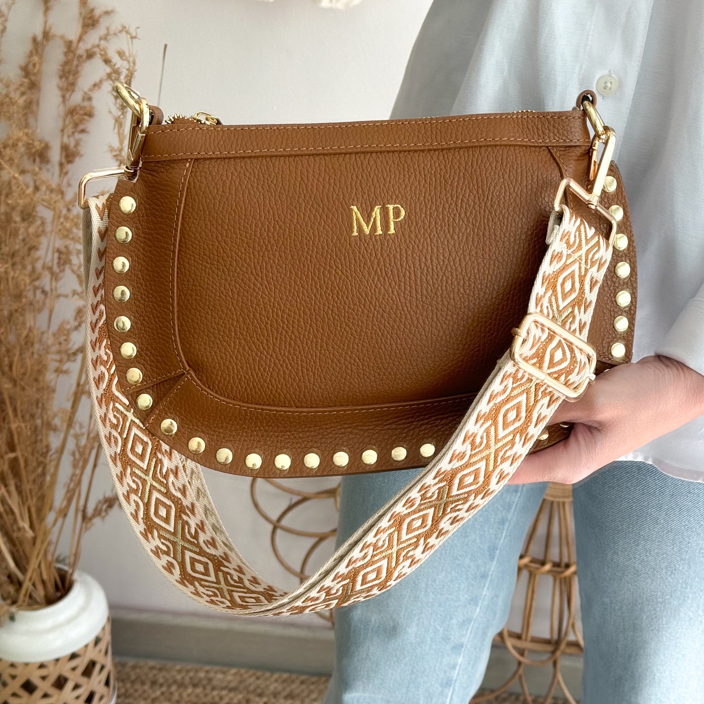 Bandolera ovalada piel tachuelas camel iniciales bordadas