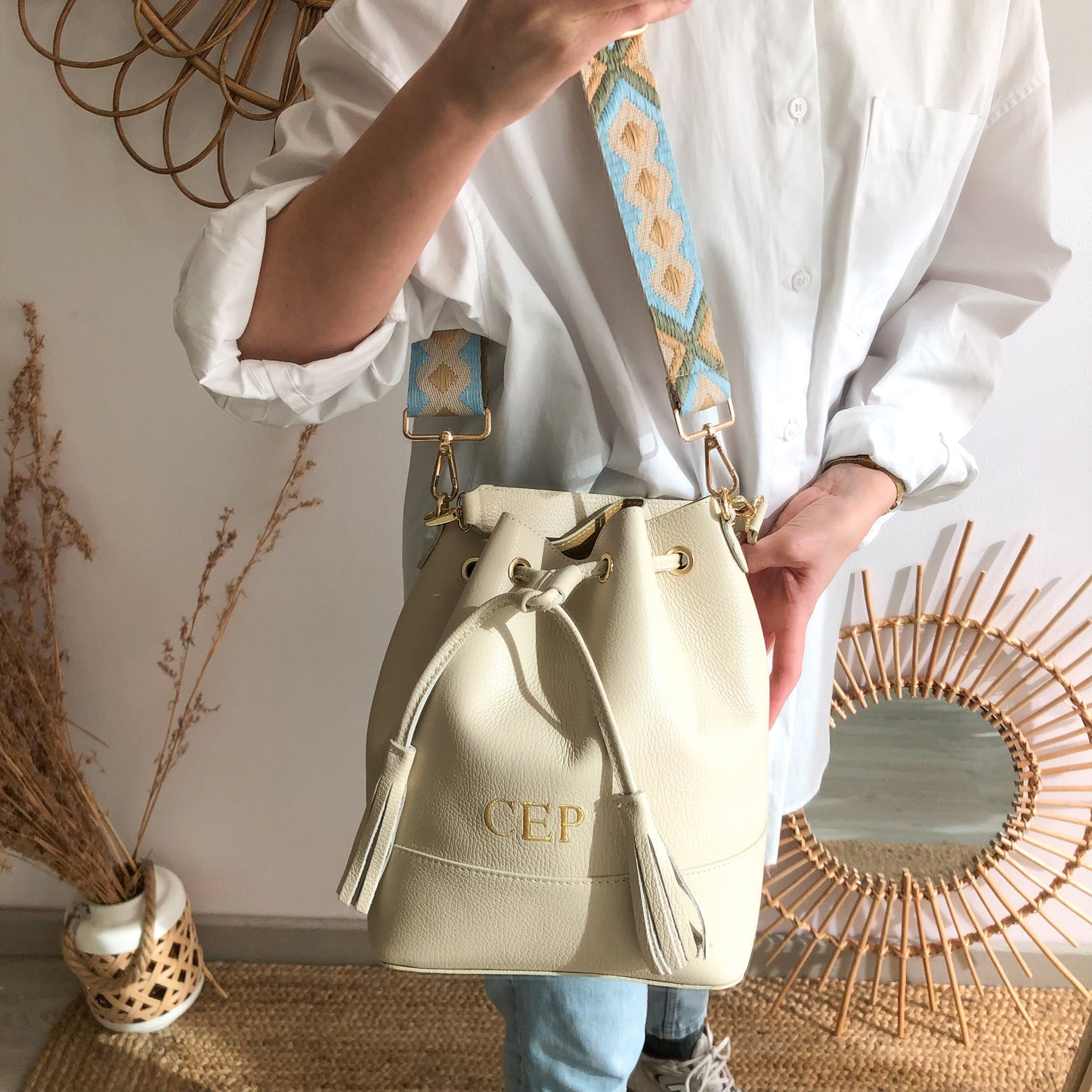 Bolso bucket piel beige pompón iniciales bordadas