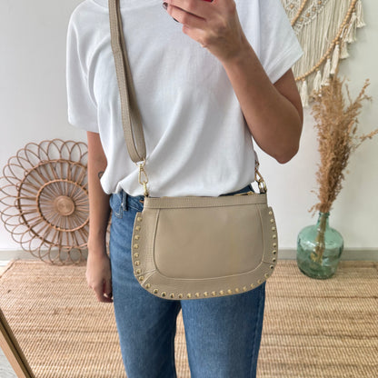 Bandolera ovalada piel tachuelas taupe iniciales bordadas