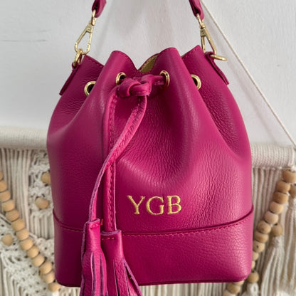 Bolso bucket piel fucsia pompón iniciales bordadas