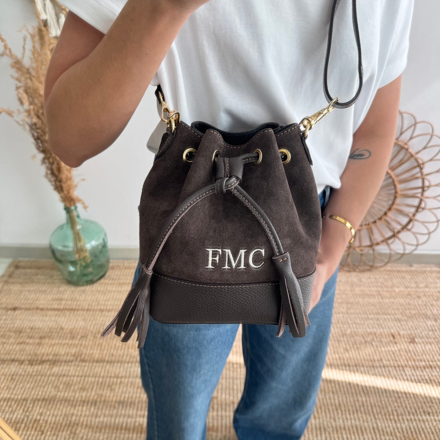 Bolso bucket serraje y piel marrón pompón iniciales bordadas