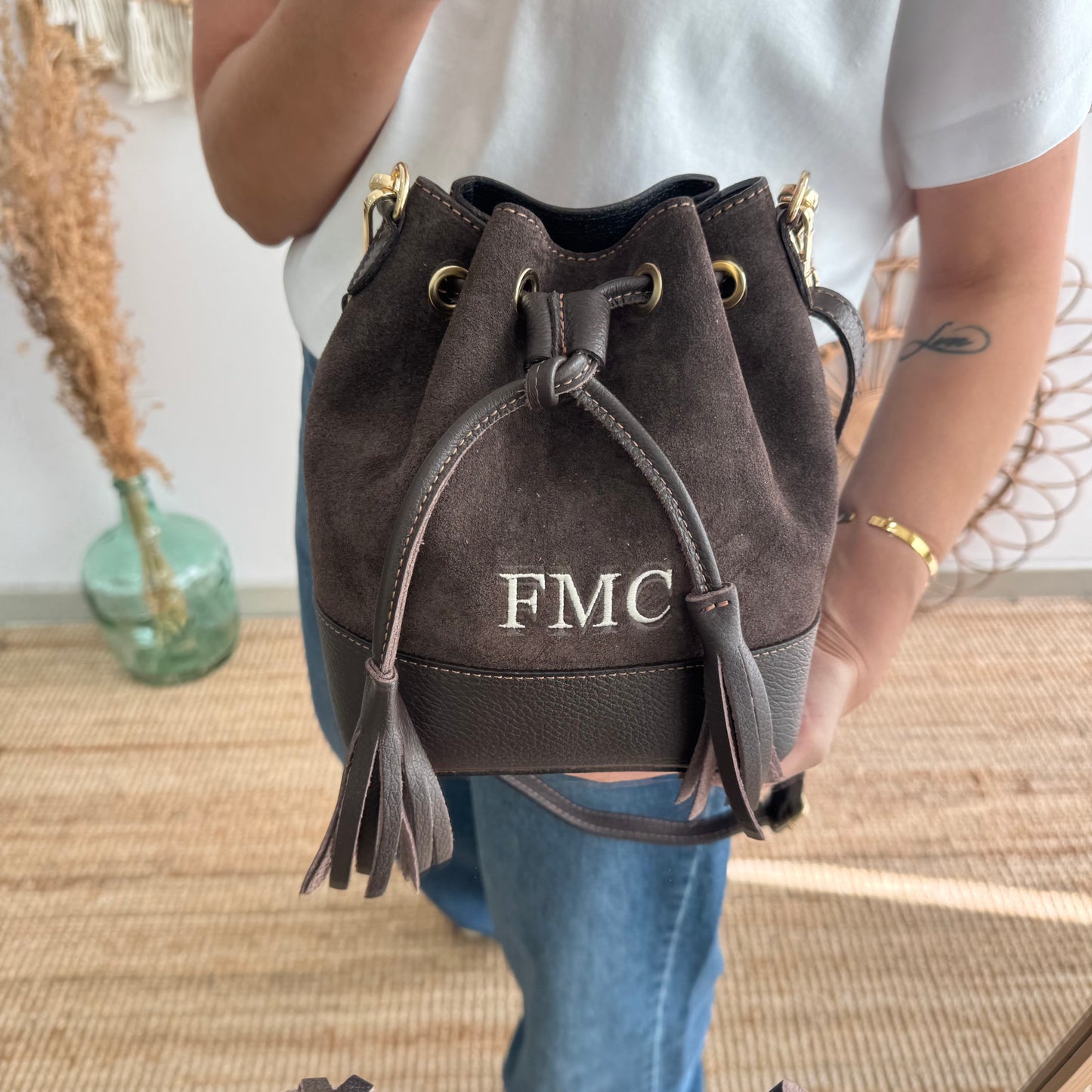 Bolso bucket serraje y piel marrón pompón iniciales bordadas