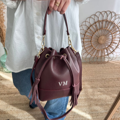 Bolso bucket piel granate pompón iniciales bordadas