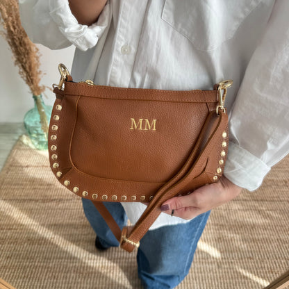 Bandolera ovalada piel tachuelas camel iniciales bordadas