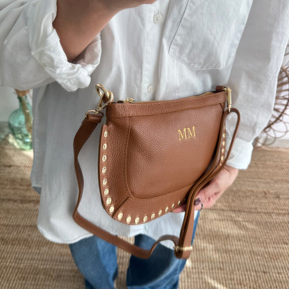 Bandolera ovalada piel tachuelas camel iniciales bordadas