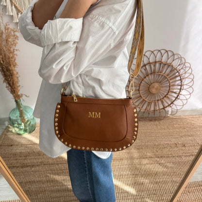 Bandolera ovalada piel tachuelas camel iniciales bordadas