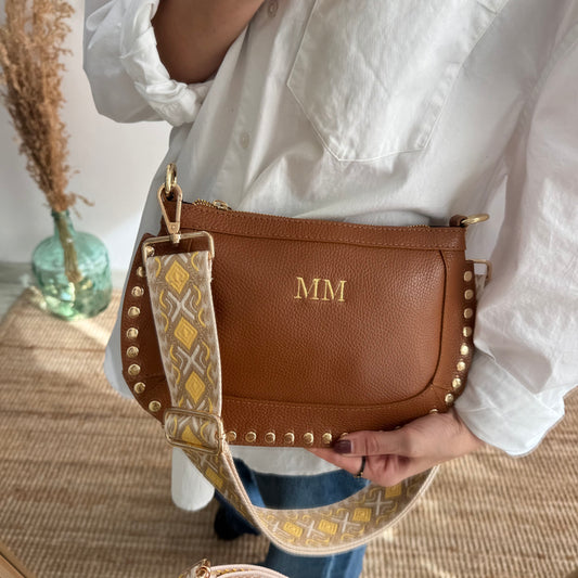 Bandolera ovalada piel tachuelas camel iniciales bordadas