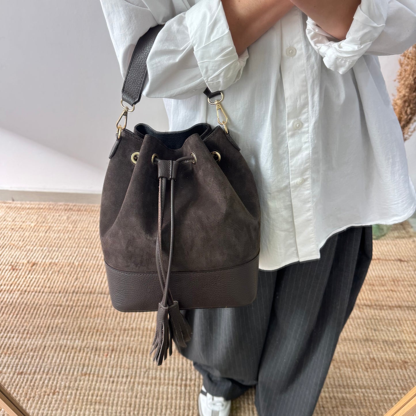 Bolso bucket serraje y piel marrón grande pompón iniciales bordadas