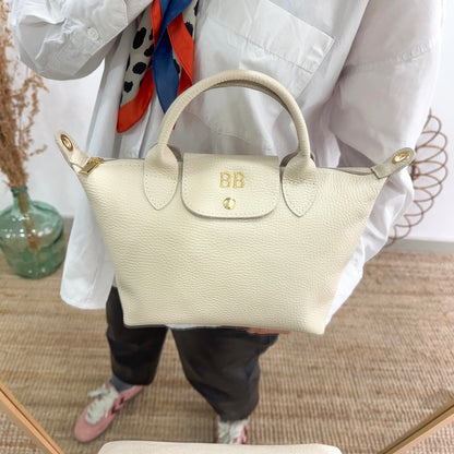 Bolso ovalado piel beige solapa iniciales bordadas