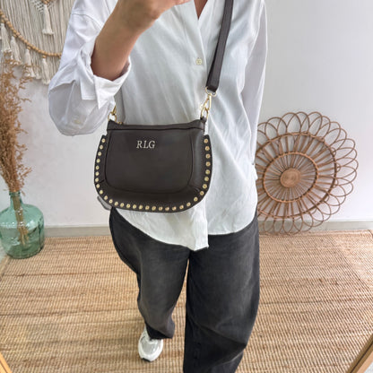 Bandolera ovalada piel tachuelas marrón iniciales bordadas