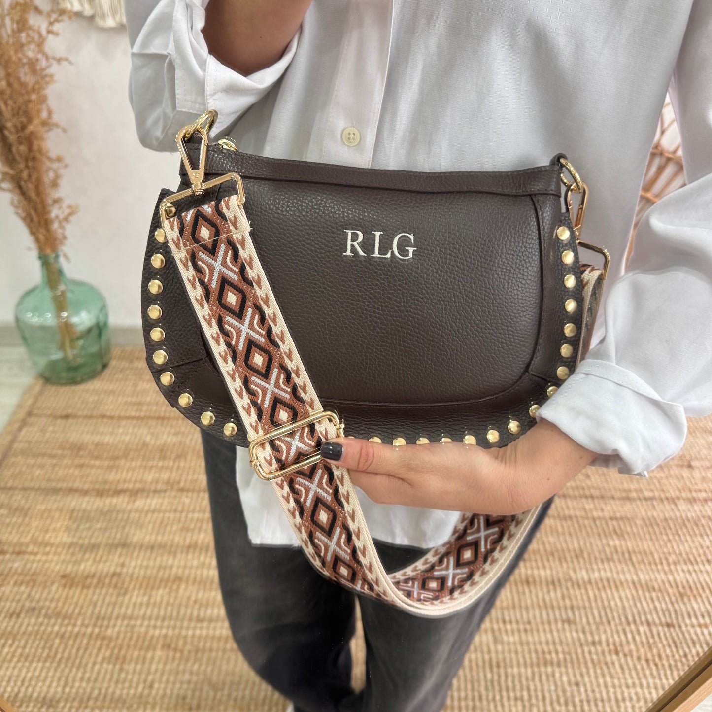 Bandolera ovalada piel tachuelas marrón iniciales bordadas