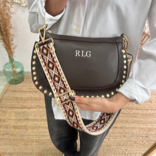 Bandolera ovalada piel tachuelas marrón iniciales bordadas