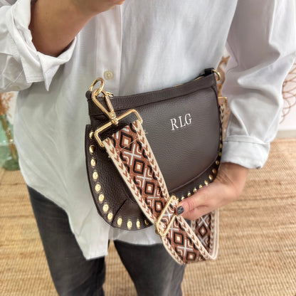 Bandolera ovalada piel tachuelas marrón iniciales bordadas