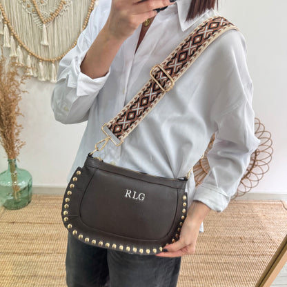 Bandolera ovalada piel tachuelas marrón iniciales bordadas