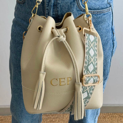 Bolso bucket piel beige grande pompón iniciales bordadas