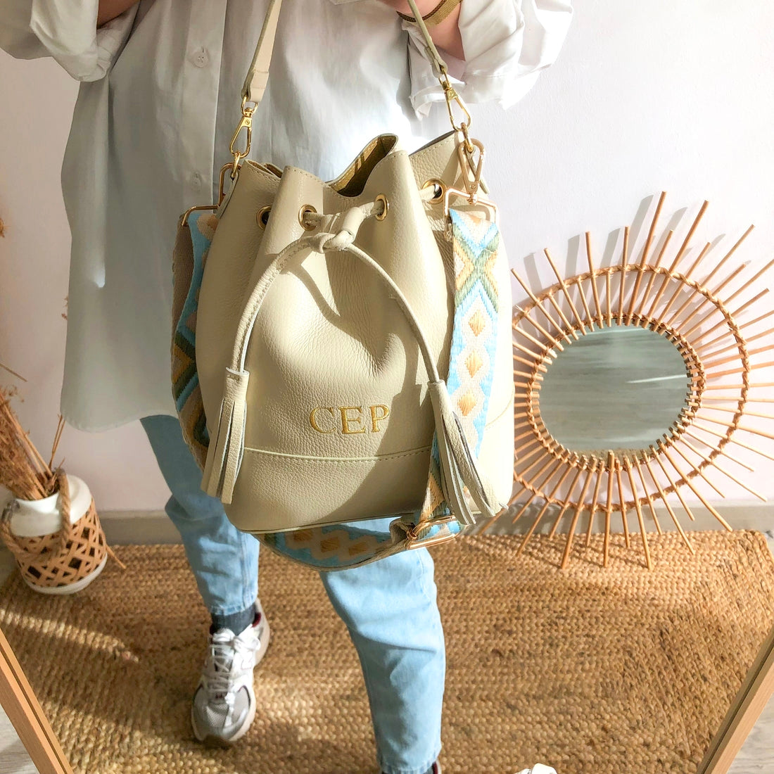 Bolso bucket piel beige grande pompón iniciales bordadas