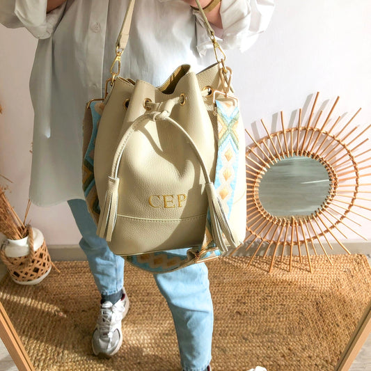 Bolso bucket piel beige grande pompón iniciales bordadas