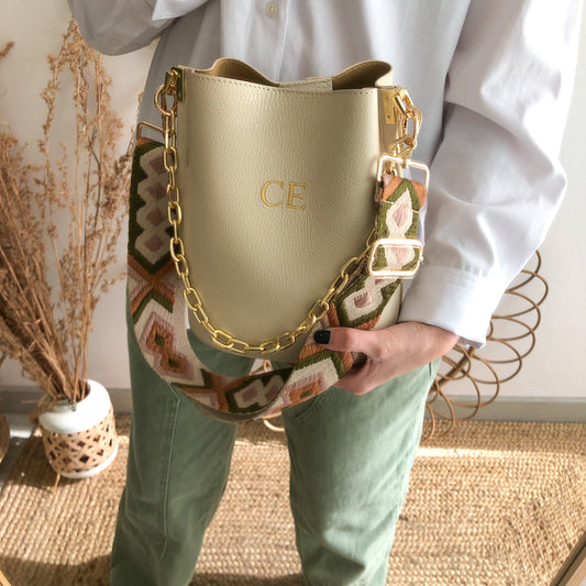 Bolso bucket piel beige cadena dorada iniciales bordadas