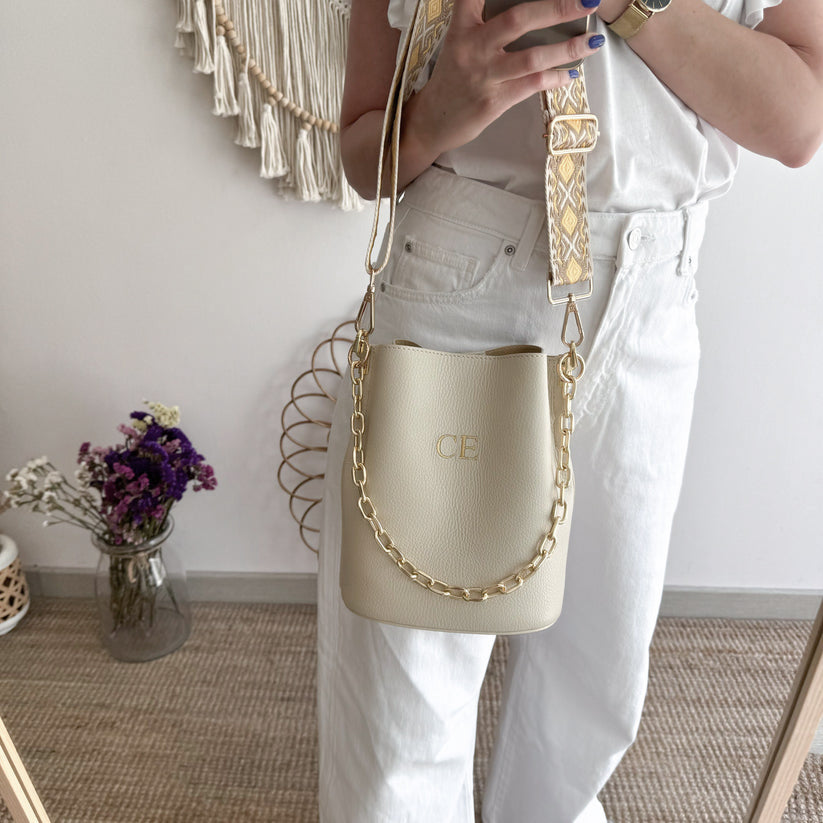 Bolso bucket piel beige cadena dorada iniciales bordadas